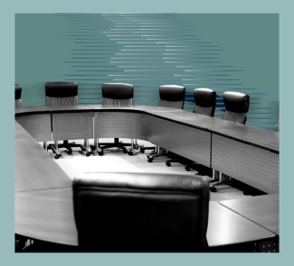 An empty board room with chairs around an oval meeting table.